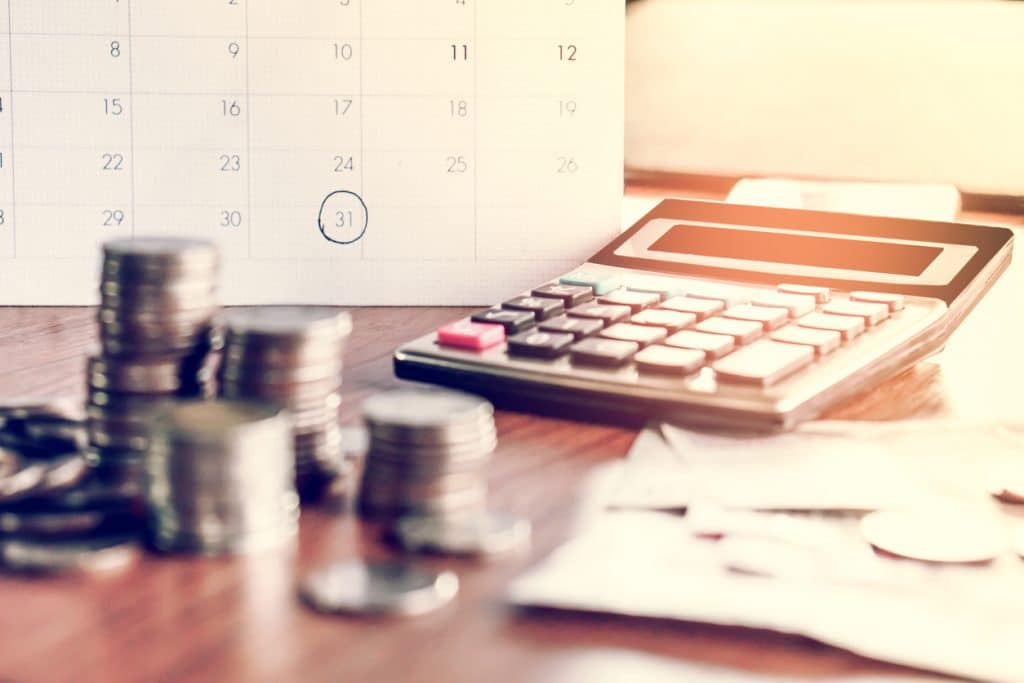 期限カレンダーと債権回収と税の季節の概念は、ノート、コイン、銀行、テーブルの上に電卓、背景、支払いの時間を思い出させる概念