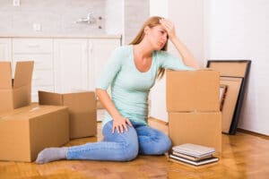 Tired woman sitting on the floor while moving into new home concept.