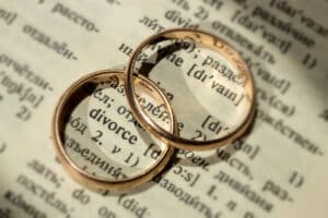 Two separate wedding rings next to the word "divorce". The concept of divorce, parting, infidelity . Selective focus concept.