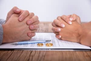 Couple's Hand With Divorce decree Agreement And Wedding Rings