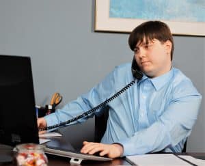 Employee on his work computer talking on the phone.